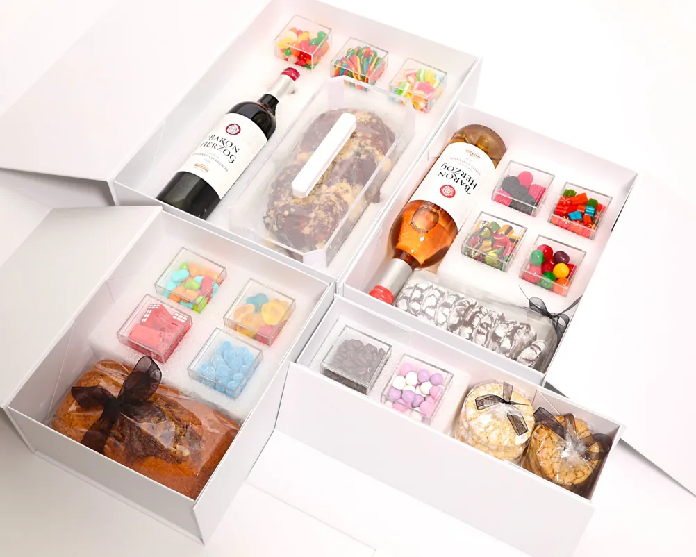 Four filled gift boxes with wine, cakes and sweets